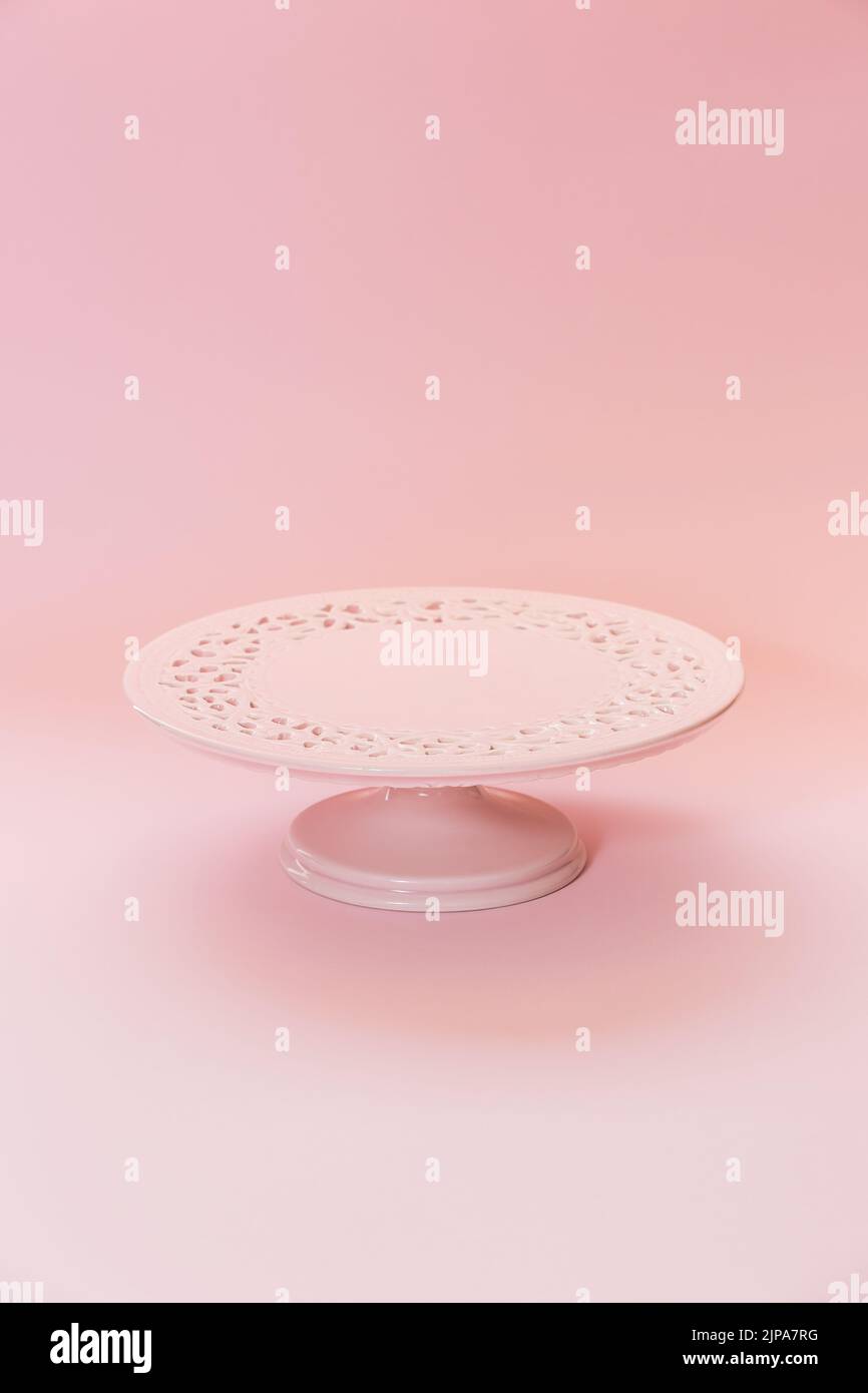 Piccolo piedistallo in ceramica rosa vuoto su un tavolo rosa pastello. Messa a fuoco selettiva, spazio di copia Foto Stock