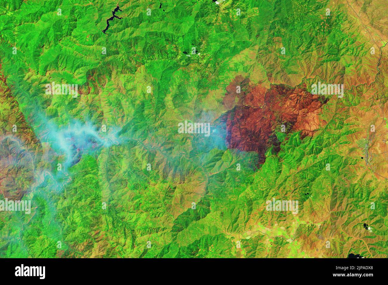 McKinney, California, Stati Uniti. 6th ago, 2022. Più di una settimana dopo l'accensione, il McKinney Fire continuò a bruciare attraverso la Klamath National Forest nella California settentrionale. Nel 2022 è stato il più grande e letale incendio dello stato. Il paesaggio e il fumo che bruciano attivamente fuochi sono visibili nelle immagini qui sopra. Le immagini sono state acquisite il 6 agosto 2022 dall'Operational Land Imager (oli) su Landsat 8. L'immagine a falsi colori (a destra) era composta da infrarosso a onde corte, infrarosso vicino e luce verde. Questa combinazione di bande (6-5-3) taglia il fumo per rivelare bu Foto Stock