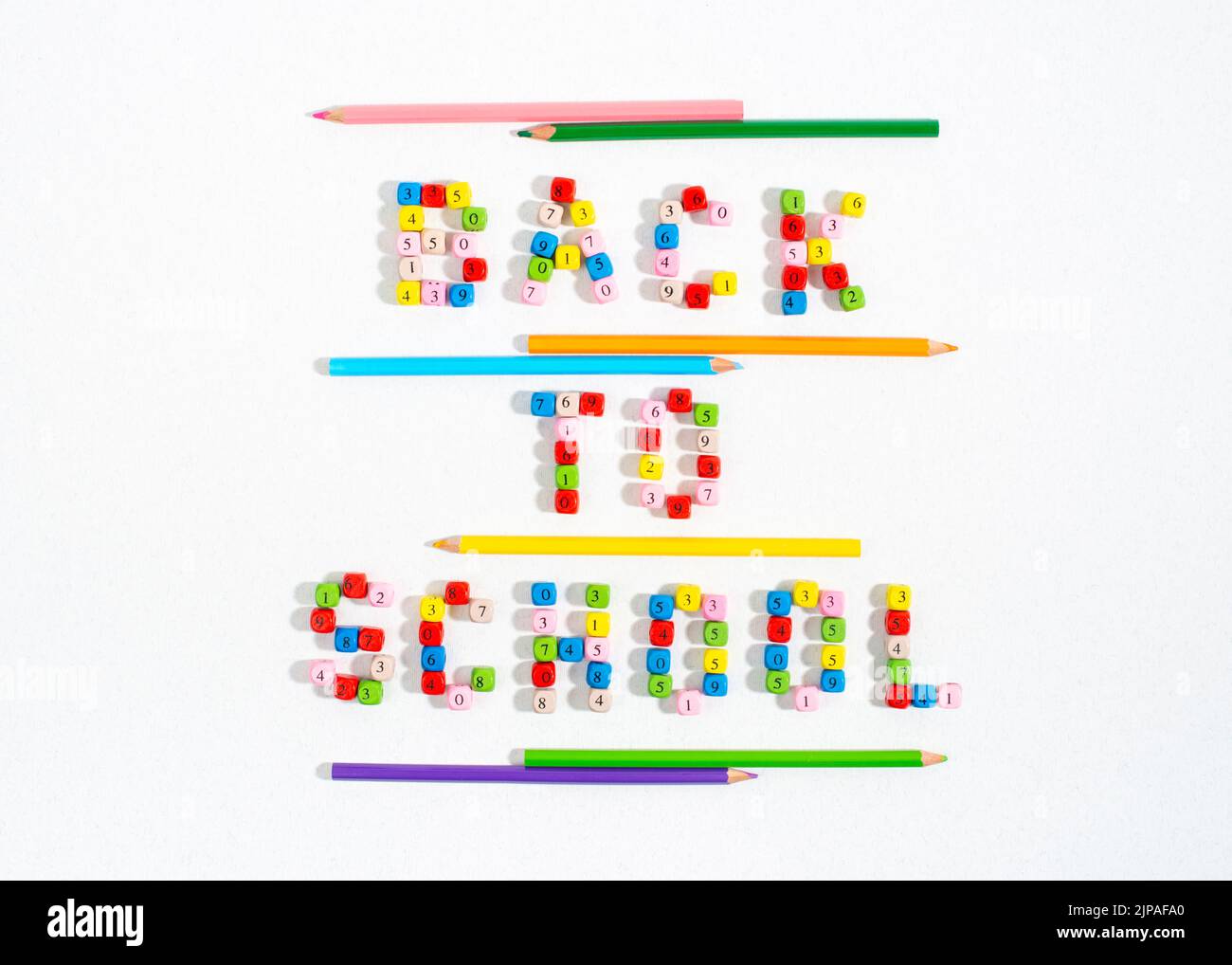 Parole di ritorno a scuola fatte di perle di numero e sottolineate con matite colorate. Foto Stock