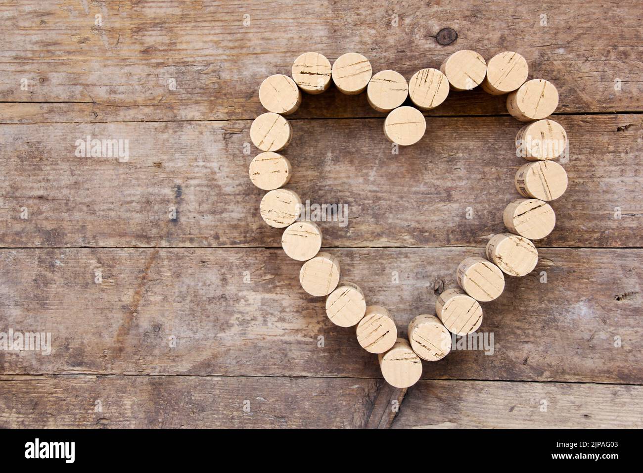 I tappi di vino formano una forma a cuore sulla tavola di legno Foto Stock