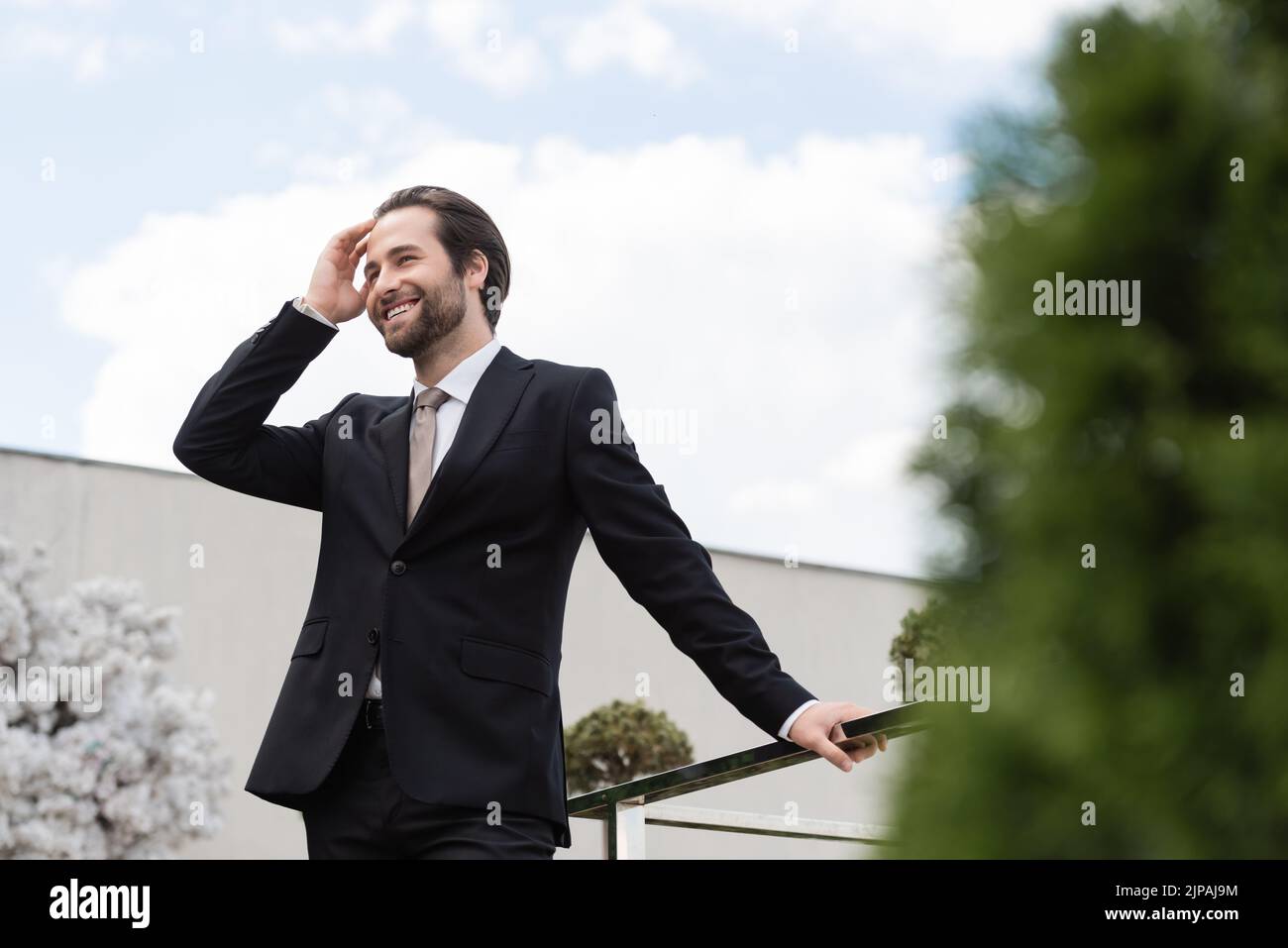 Vista a basso angolo dei capelli toccanti dello sposo positivo sulla terrazza del ristorante Foto Stock