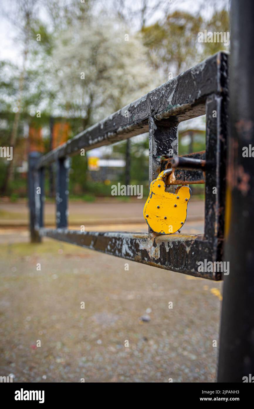 Lucchetto giallo sul palo della barriera in un'area ristretta. Foto Stock