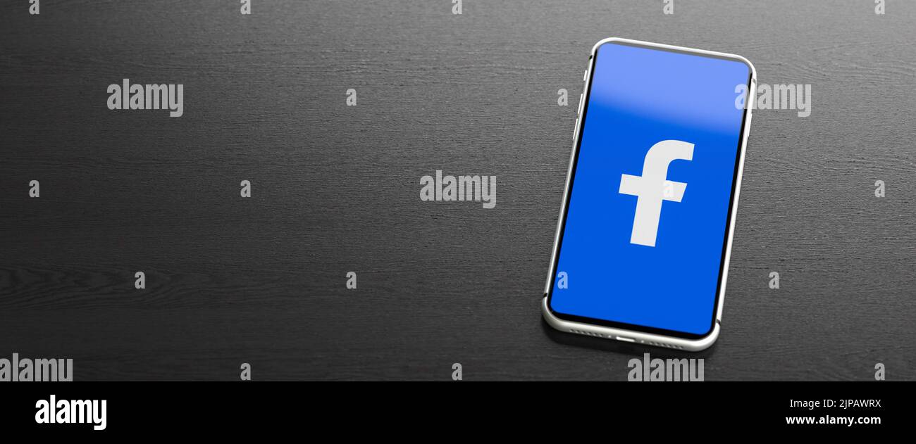 Logo del sito dei social media e dell'app Facebook su un telefono cellulare su un tavolo. Spazio di copia. Formato banner Web. Foto Stock