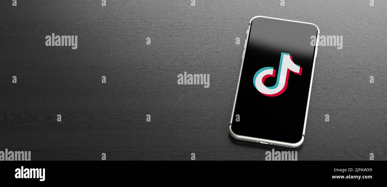 Logo del sito di video sui social media e dell'app Tiktok su un telefono cellulare su un tavolo. Spazio di copia. Formato banner Web. Foto Stock