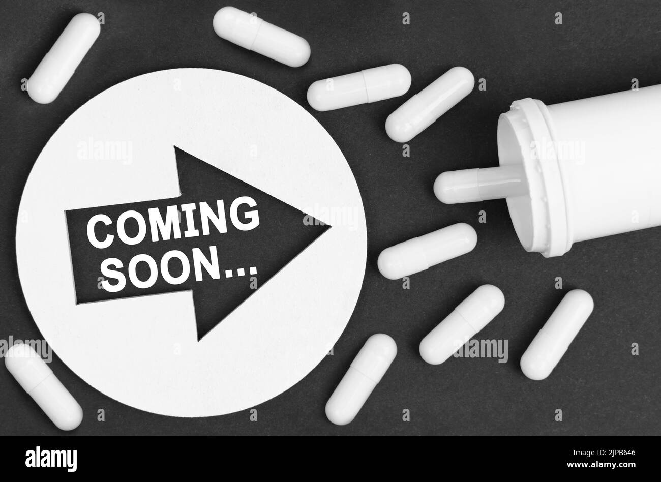 Concetto di medicina. Pillole su sfondo nero. Sono indicati da un cerchio con una freccia, all'interno del quale è scritto - PROSSIMAMENTE Foto Stock