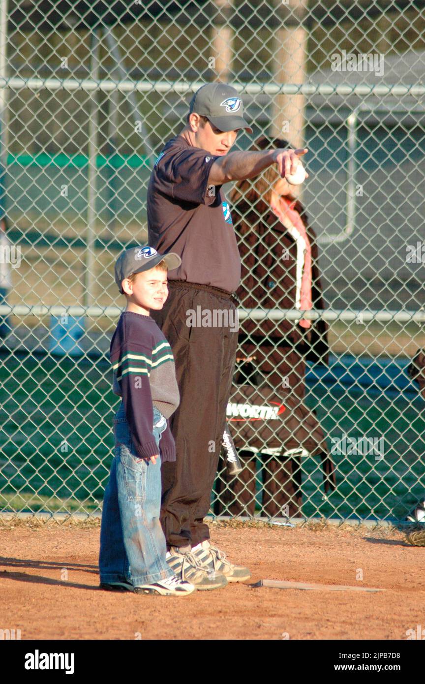Giovani e allenatori su campi sportivi durante gli sport primaverili, allenati e giocati, partite di baseball Foto Stock