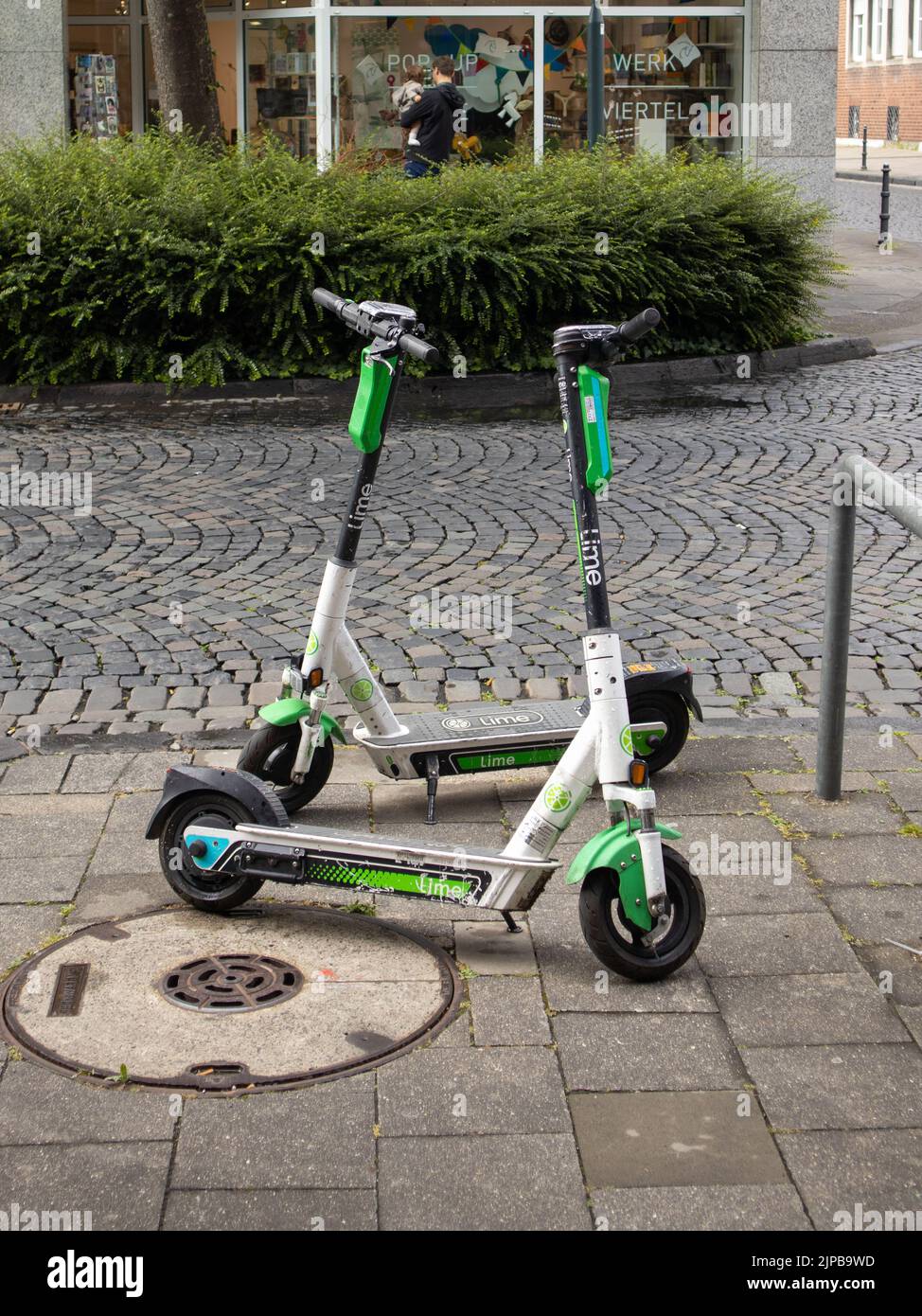Uno scatto verticale di due scooter elettrici Lime parcheggiati sulla strada Foto Stock