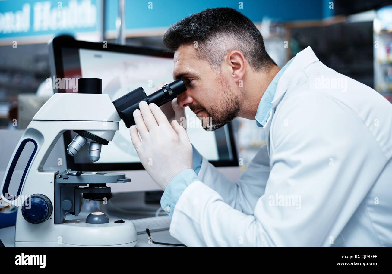 Migliorare la vita dei pazienti con una ricerca clinica meticolosa. Un uomo maturo che usa un microscopio mentre conduce la ricerca farmaceutica. Foto Stock