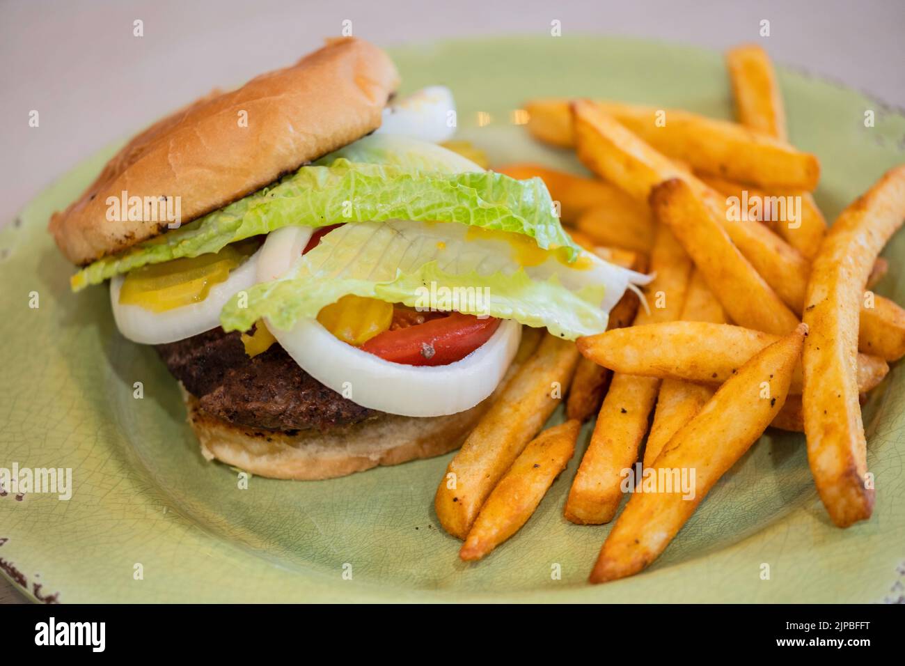Un hamburger cotto su un panino con senape, cipolla, pomodoro, sottaceti e lattuga, con patatine fritte o patatine fritte. STATI UNITI. Foto Stock