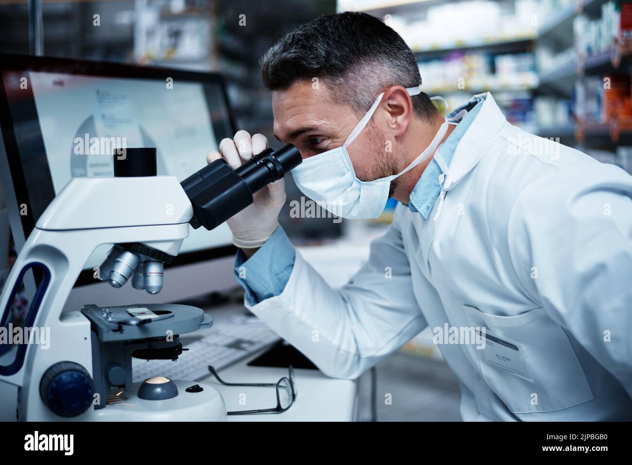 Definisce lo standard per un'eccellente ricerca clinica: Un uomo maturo che utilizza un microscopio mentre conduce ricerche farmaceutiche. Foto Stock