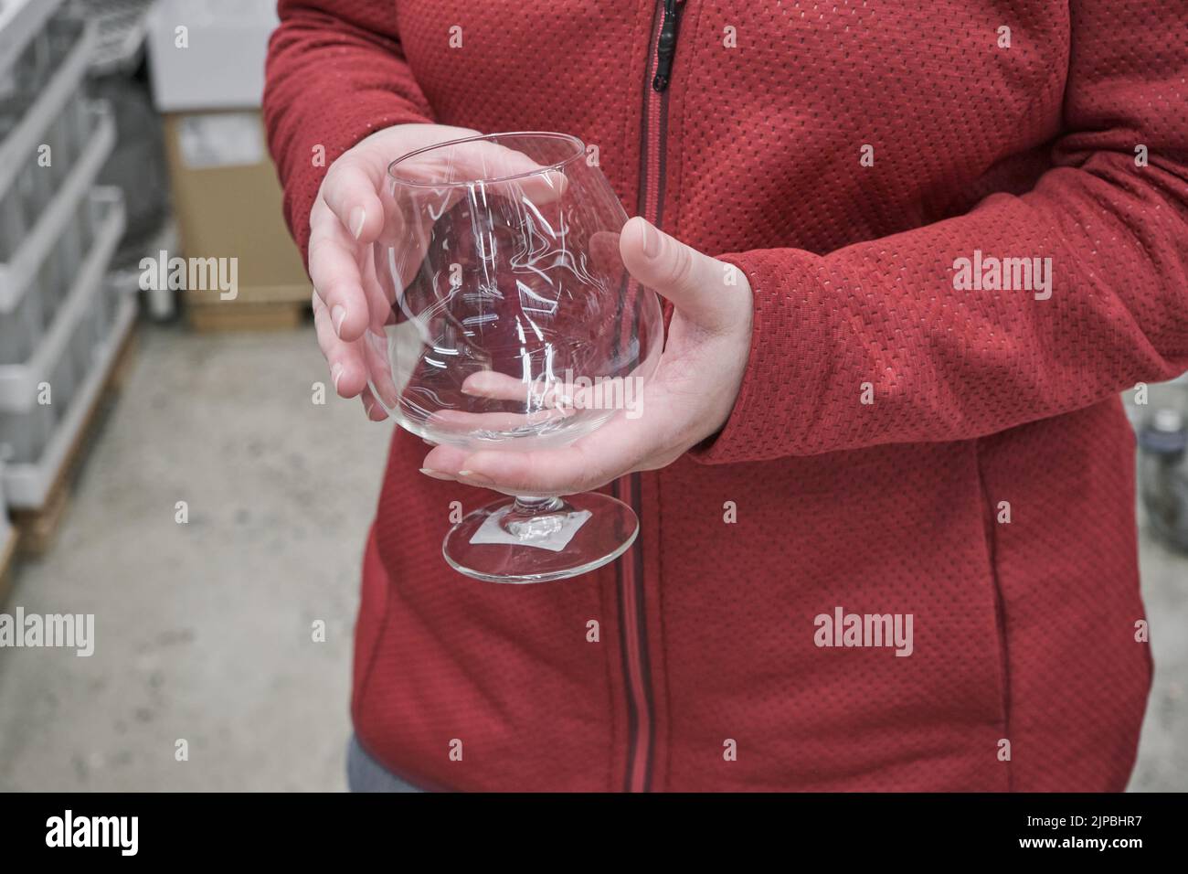 La ragazza caucasica acquista un grande bicchiere trasparente per vino e brandy in un negozio Foto Stock