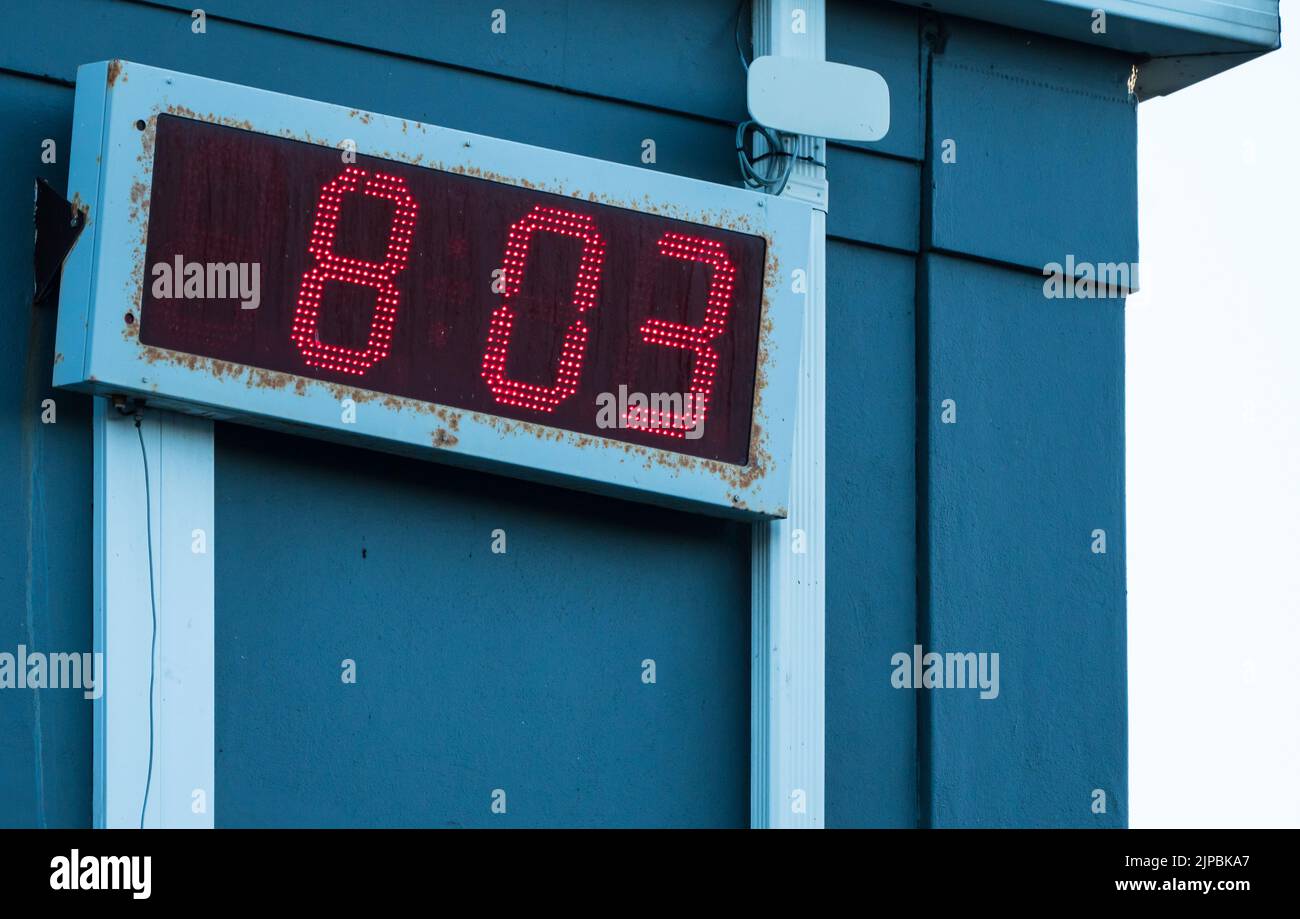 orologio digitale con luci a led rosse all'aperto su un edificio che mostra l'ora del giorno e/o la data tecnologia concettuale Foto Stock