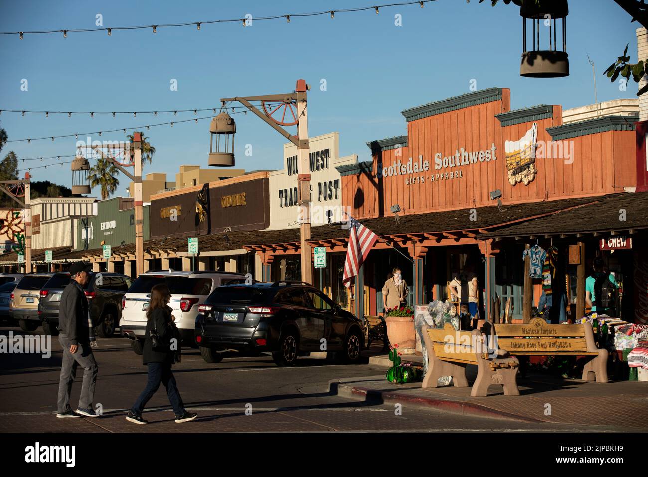 Scottsdale, Arizona, USA - 4 gennaio 2022: La luce del tardo pomeriggio splende sulle facciate storiche della città vecchia, mentre i visitatori attraversano una strada. Foto Stock