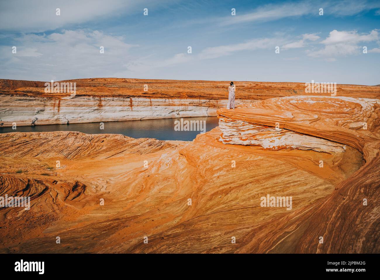 Esplorazione dell'area ricreativa nazionale di Glen Canyon. Silhouette di donna in piedi su un piano bluff, rocce rosse ondulate, e cielo nuvoloso drammatico sullo sfondo Foto Stock