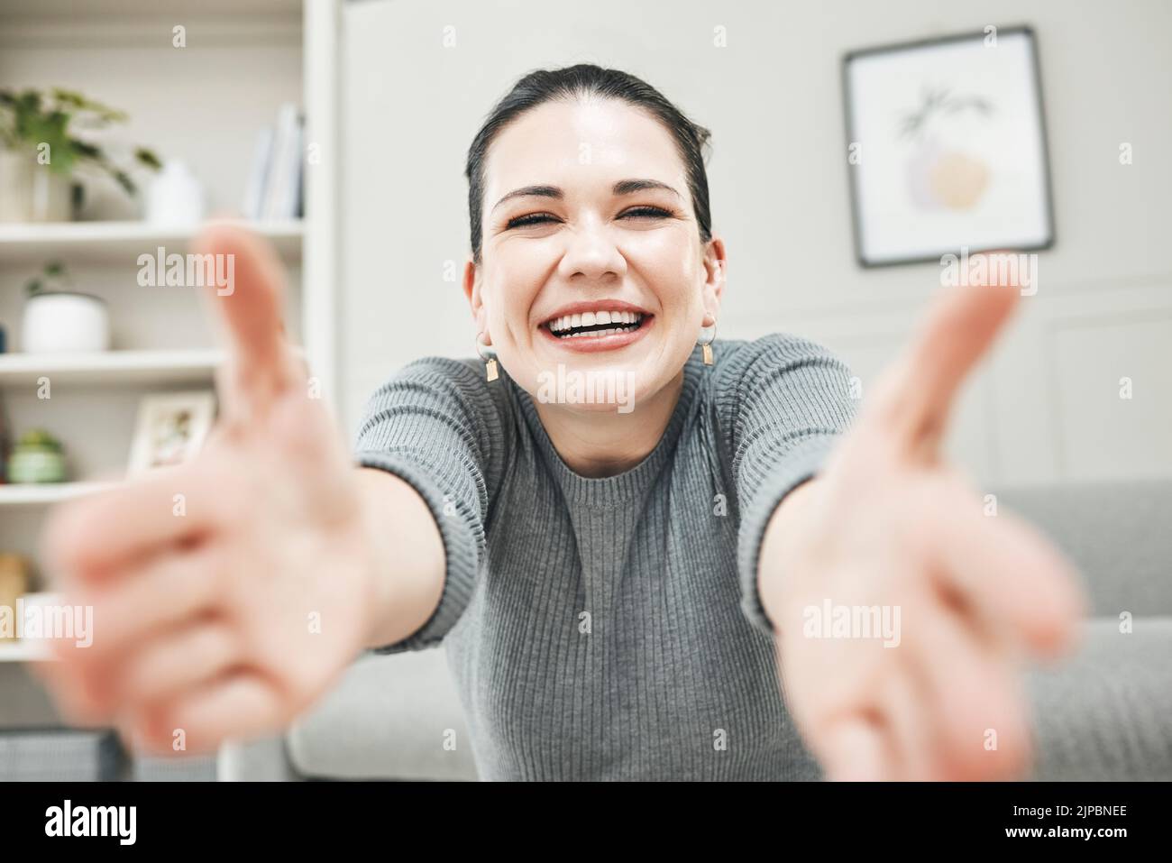 Donna felice, sorridente e ridente che le raggiunge le braccia per un abbraccio, abbraccio o tenuta mentre si rilassa da sola a casa. Ritratto di un rilassato, contenuto e. Foto Stock
