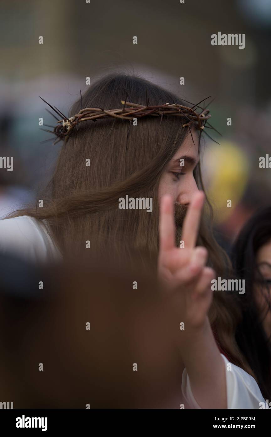 La vista verticale di una ragazza con una corona di spine sulla testa che mostra il segno di pace con le dita Foto Stock