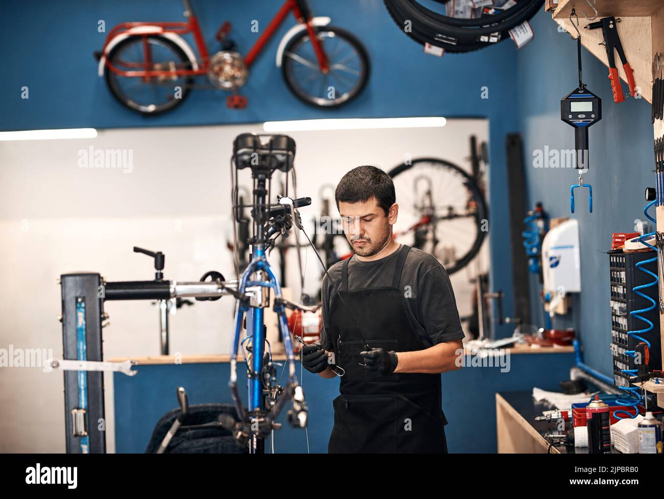 Fare ciò che fa meglio, riparare una bicicletta. Un uomo che lavora in un negozio di riparazione di biciclette. Foto Stock