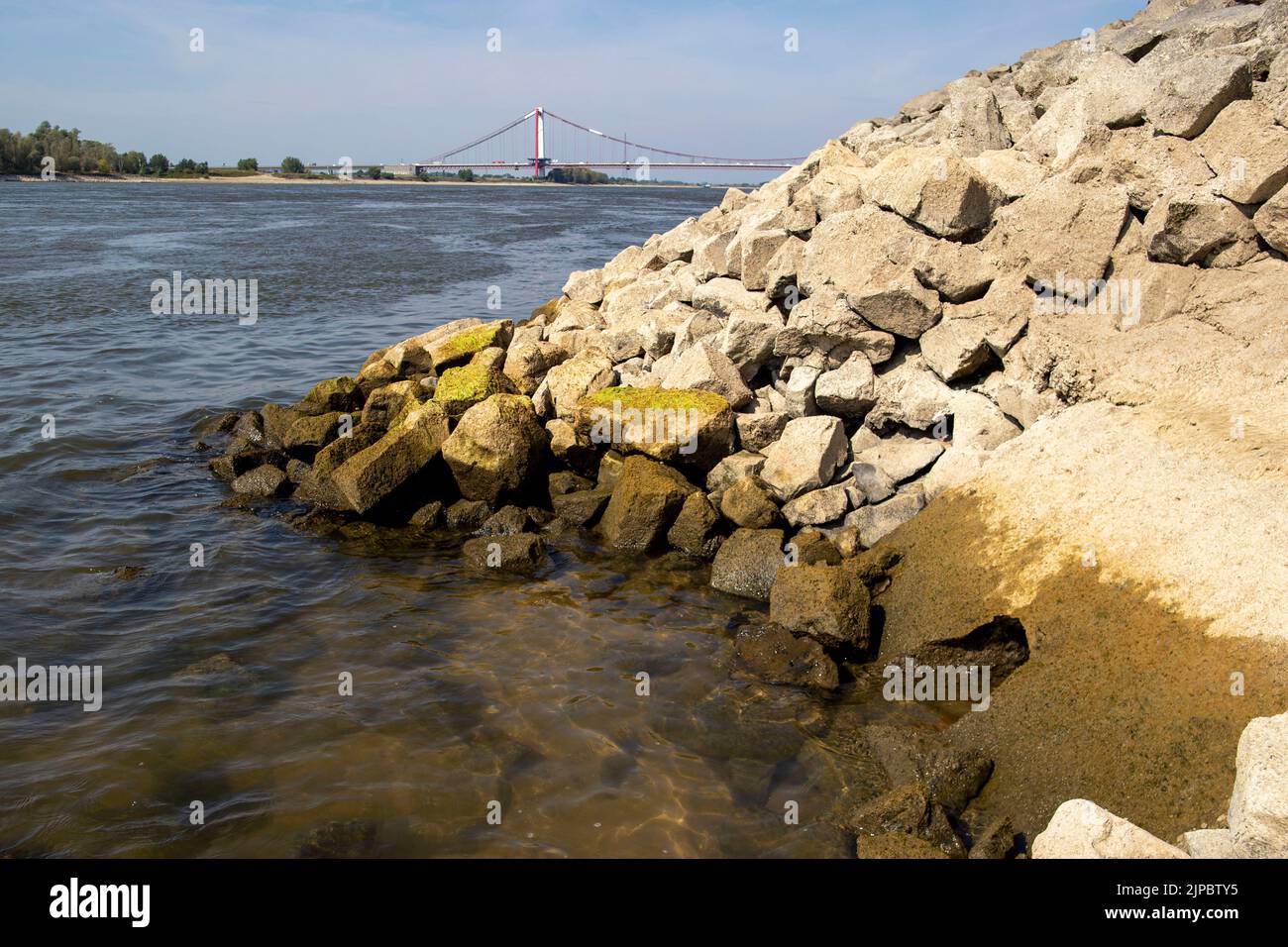 Emmerich, Germania. 16th ago, 2022. Sulla destra nella pietra un buco, attraverso questo l'acqua del Reno è condotta al misuratore d'acqua e misurata lì. Sullo sfondo, il ponte sul Reno di Emmerich. Acqua bassa sul Reno, il livello di Emmerich scende a zero. Credit: Christoph Reichwein/dpa/Alamy Live News Foto Stock