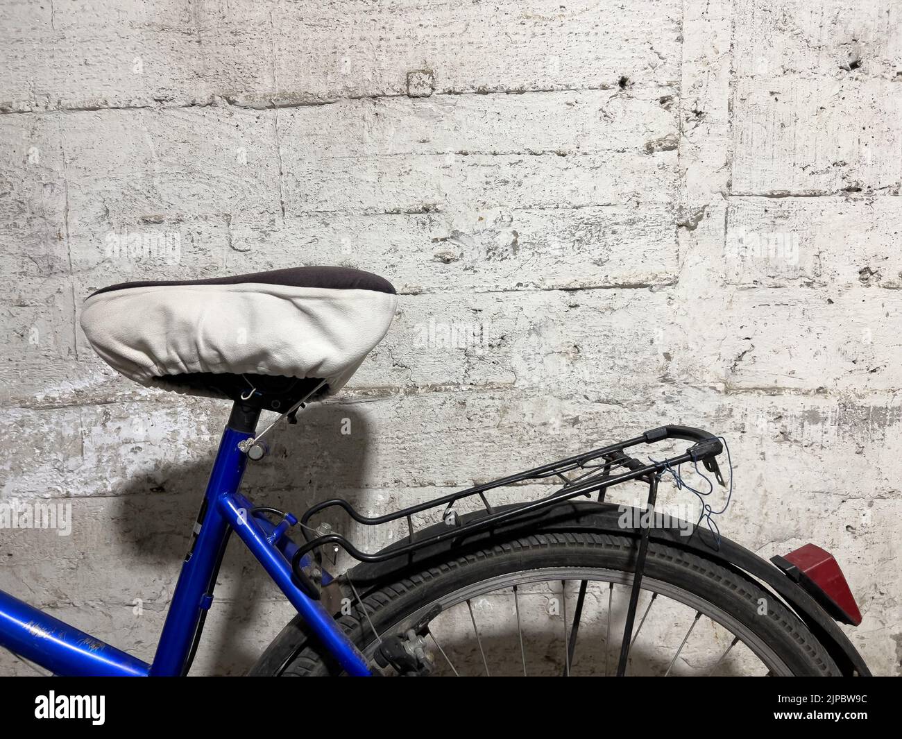 Un primo piano di un sedile per bicicletta contro una parete in cemento testurizzato Foto Stock