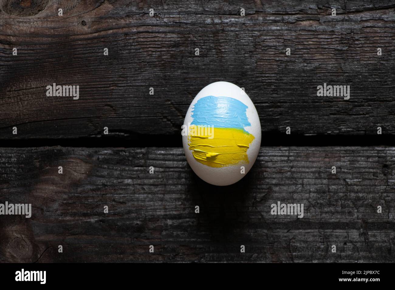 Uovo di pollo con la bandiera dell'Ucraina su uno sfondo di legno. Ucraina durante la guerra, azione di protesta, nessuna guerra, pace in Ucraina 2022 Foto Stock