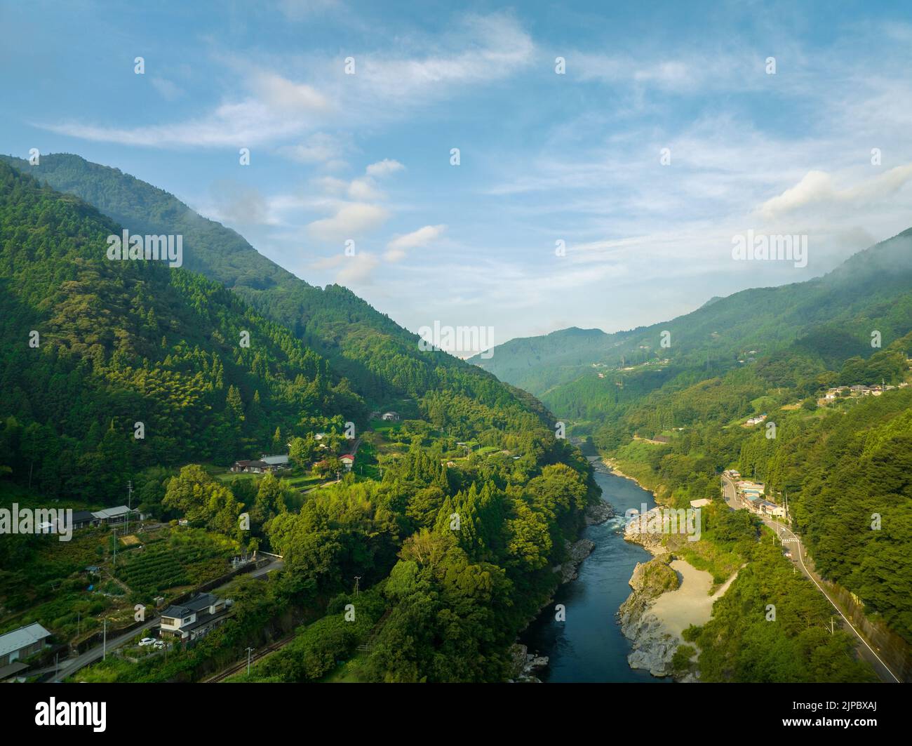Il fiume scorre attraverso la valle boschiva e piccoli villaggi al sole del mattino Foto Stock
