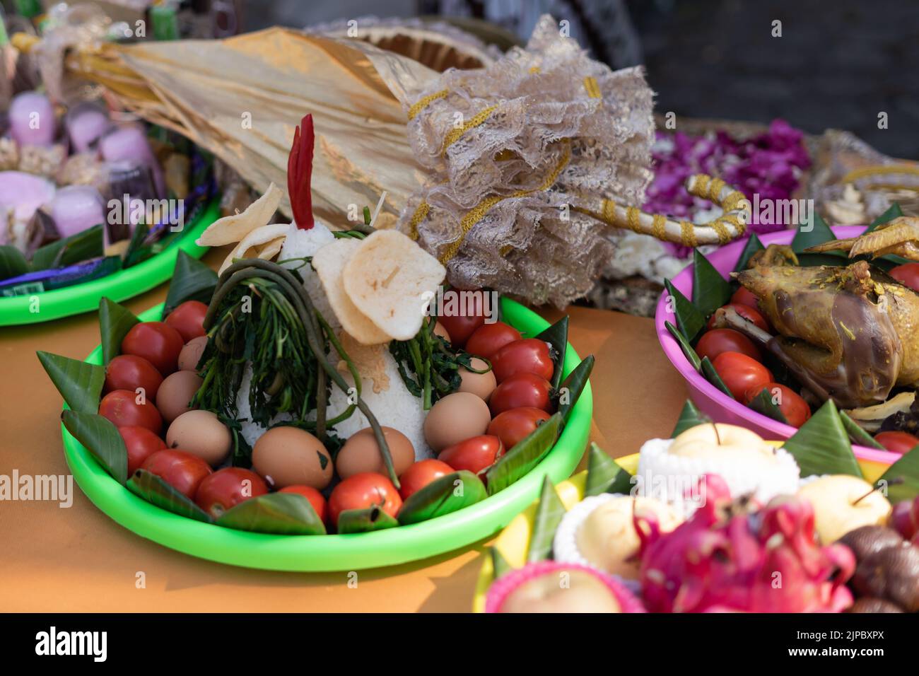 Il focus selettivo di vari alimenti di colore include frutta, verdura e pollo decorato per Siraman nel rituale tradizionale di nozze giavanese. Foto Stock