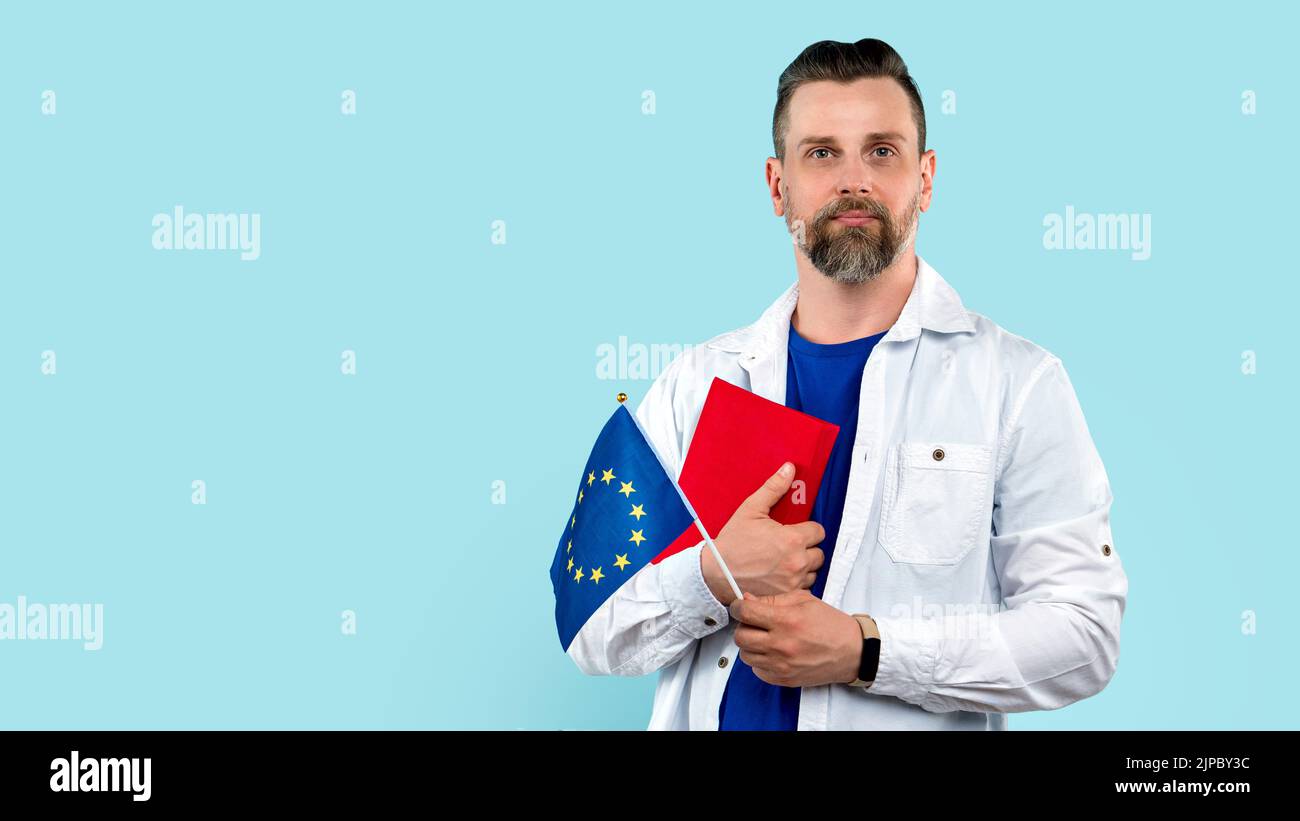 Ritratto calma uomo fiducioso e bello in camicia bianca e t-shirt blu con libro rosso e bandiera Unione europea, simbolo Europa, UE, istruzione ab Foto Stock