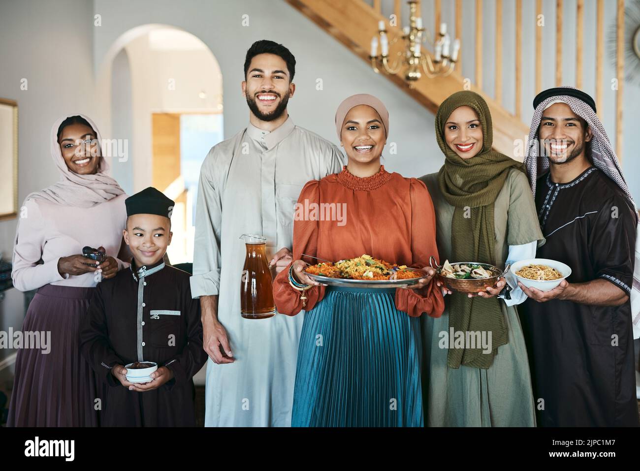 Famiglia musulmana sorridente e festosa che festeggia l'eid o il pranzo del ramadan, tenendo piatti di cibo a casa. Religione islamica felice e tradizionale Foto Stock