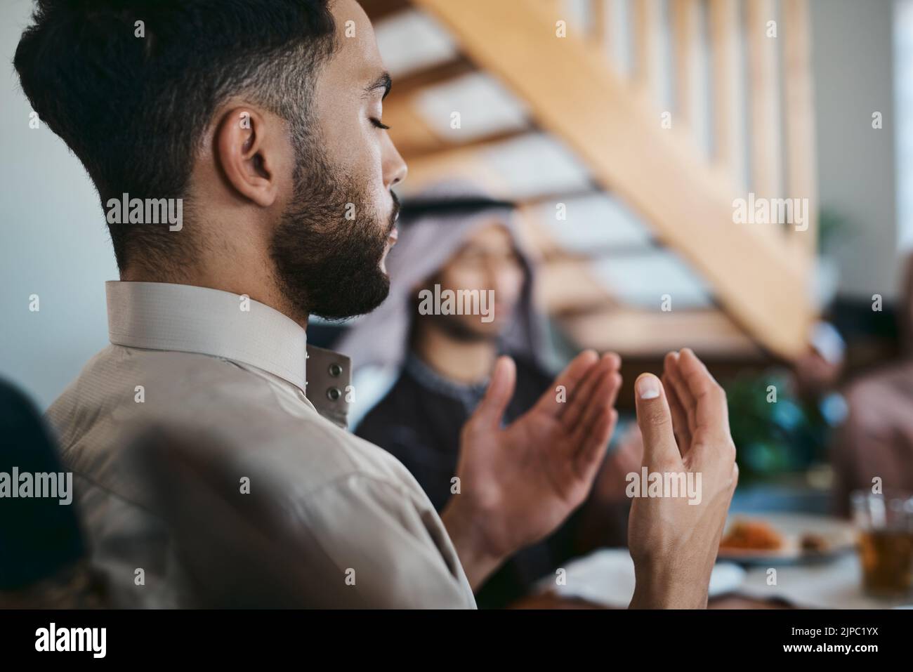 Musulmano, pregando e religione mentre si siede con la famiglia e dire un dua o la preghiera prima di rompere il digiuno durante il mese santo di Ramadan. Uomo religioso Foto Stock
