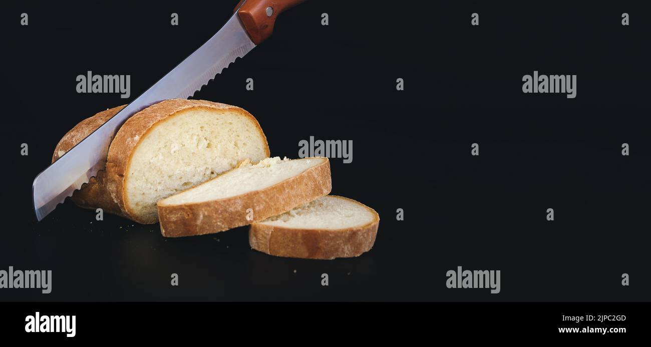Coltello per affettare una pagnotta appena sfornata. Pane di semi, pane fatto in casa, pane da taglio Foto Stock