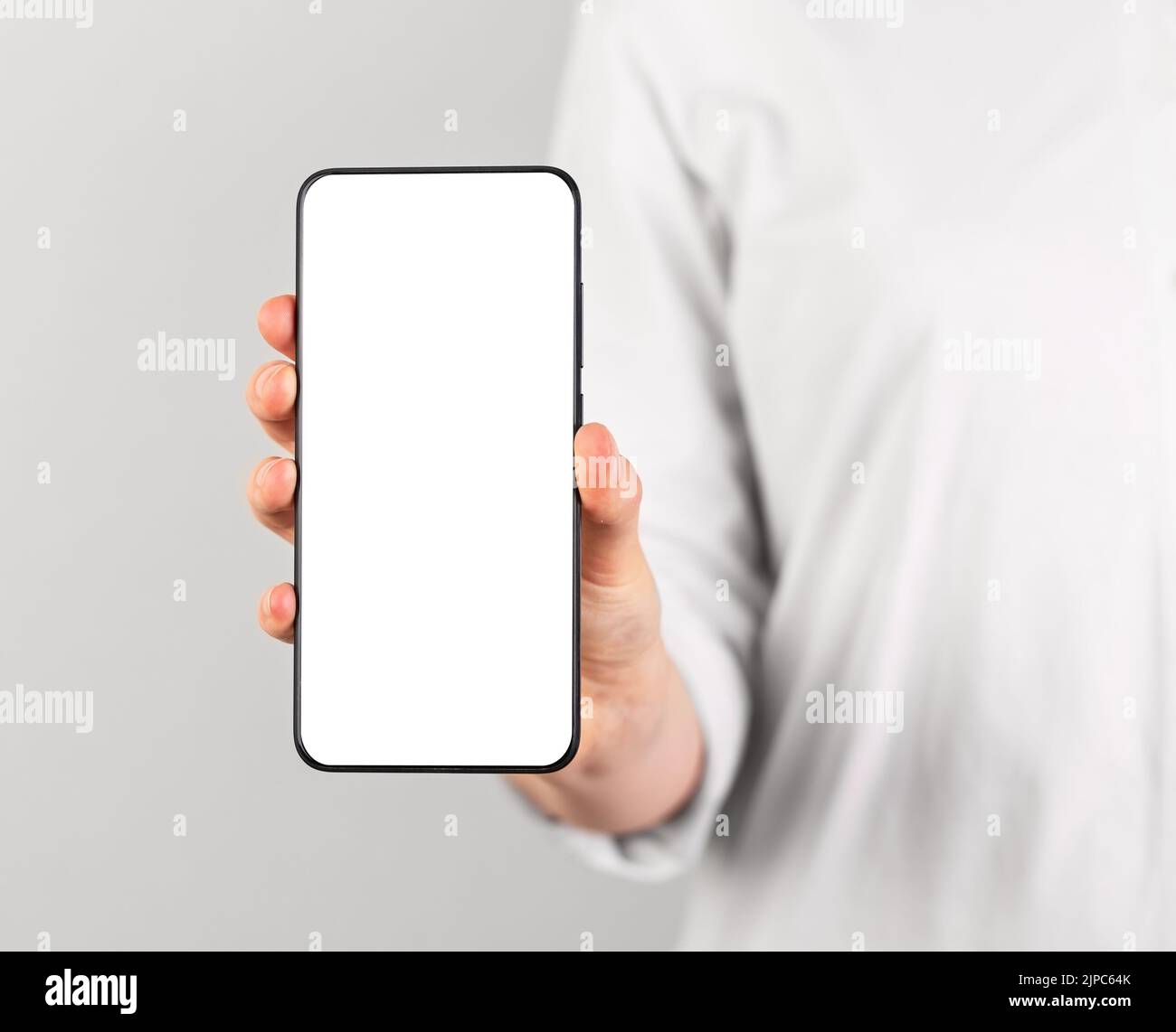 Donna che tiene il mockup del telefono in posizione verticale. Donna che utilizza lo smartphone per mostrare foto o informazioni. Modello telefonico con display vuoto. Alto Foto Stock
