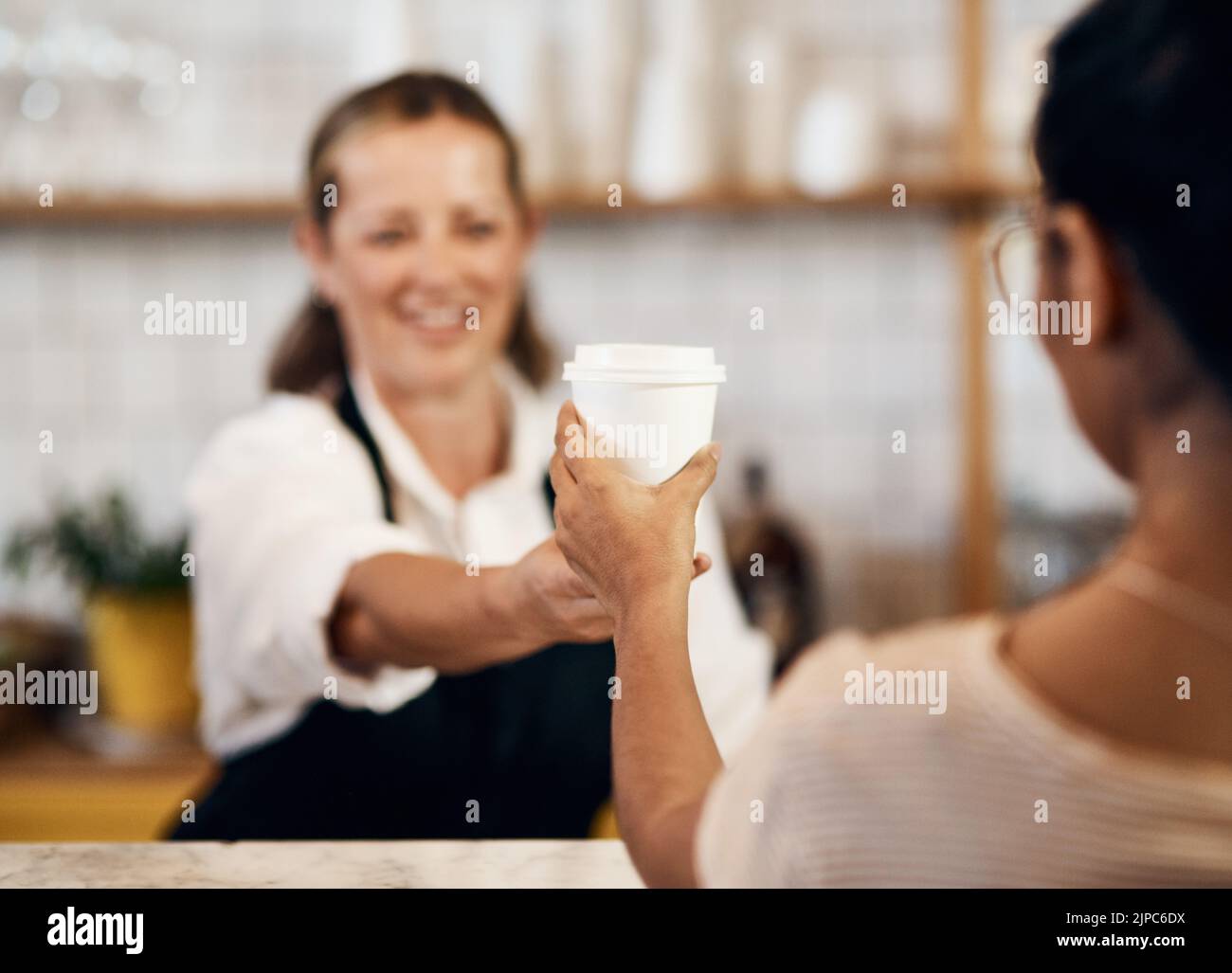 Cliente che acquista una tazza di caffè caldo da un felice barista che offre un servizio buono e cordiale in un bar locale. Sorridente imprenditore e proprietario di startup Foto Stock