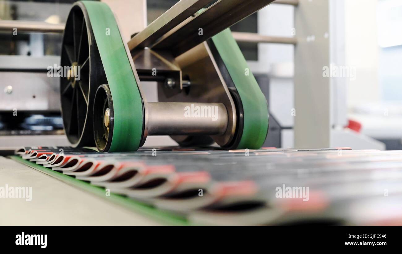 Soft focus di piegatura automatica e cucitura di opuscoli su nastro trasportatore durante il giorno in tipografia Foto Stock