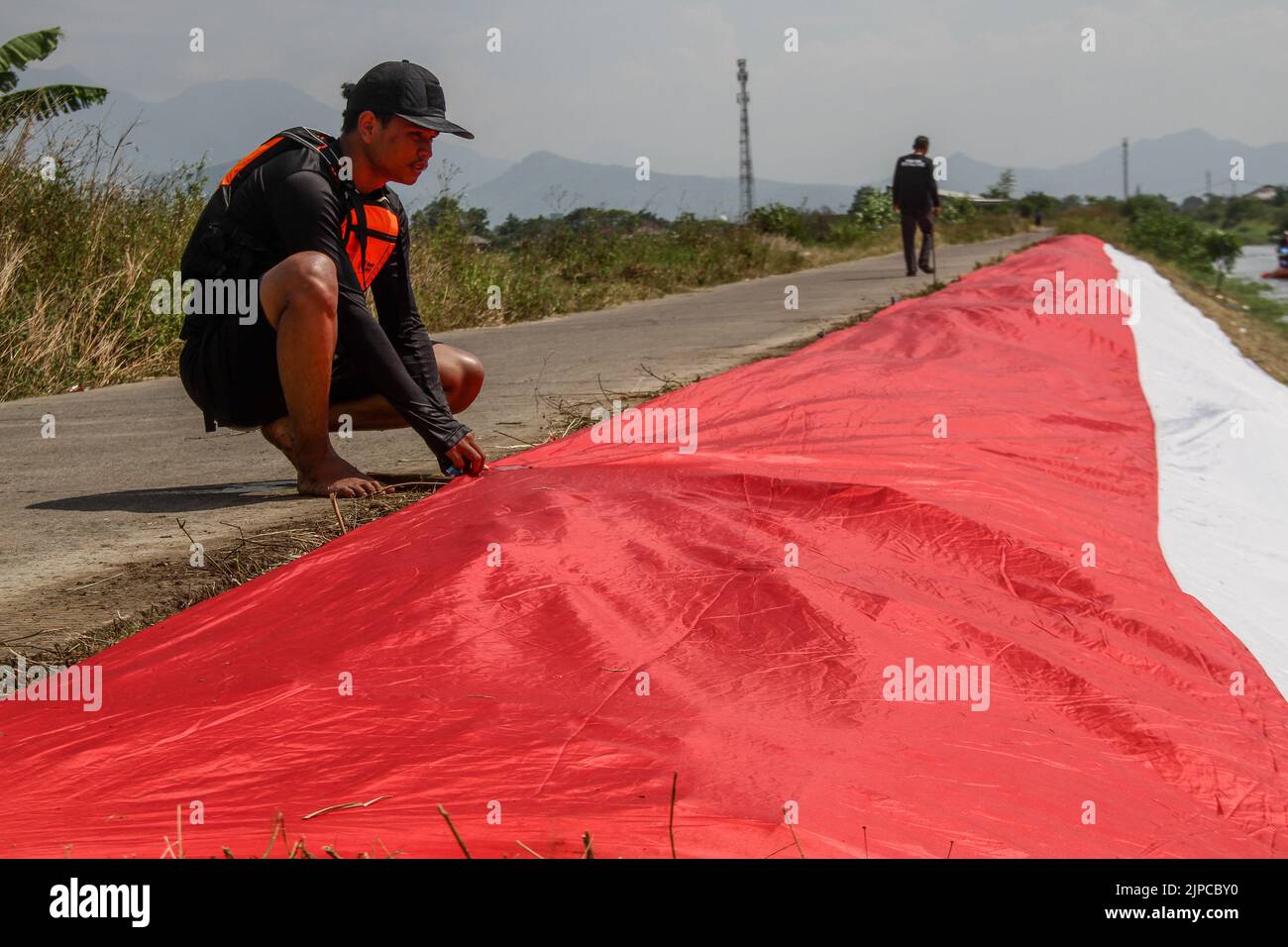 Rancaekek, Giava Occidentale, Indonesia. 17th ago, 2022. I membri della comunità Rancaekek River and Ecosystem Crossing Force (PASSER) hanno tenuto una cerimonia durante la celebrazione dell'Indonesia Independence Day nel fiume Cikijing, Rancaekek. L'installazione di un panno rosso e bianco lungo 77 metri da parte dei membri della Comunità della forza di attraversamento del fiume Rancaekek e dell'ecosistema (PASSANTE) della reggenza di Rancaekek sul fiume cikijing è stata tenuta in commemorazione del 77th° anniversario della Repubblica di Indonesia. (Credit Image: © Algi Libri Sugita/ZUMA Press Wire) Foto Stock