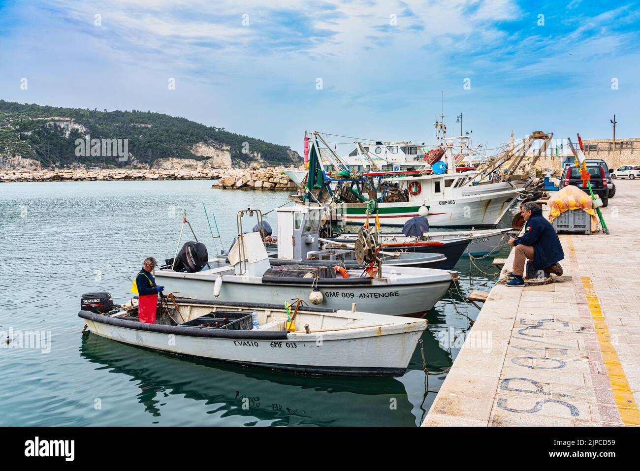 Pescatori che lavorano sulle reti da pesca nel porto di Peschici. Peschici, provincia di Foggia, Puglia, Italia, Europa Foto Stock
