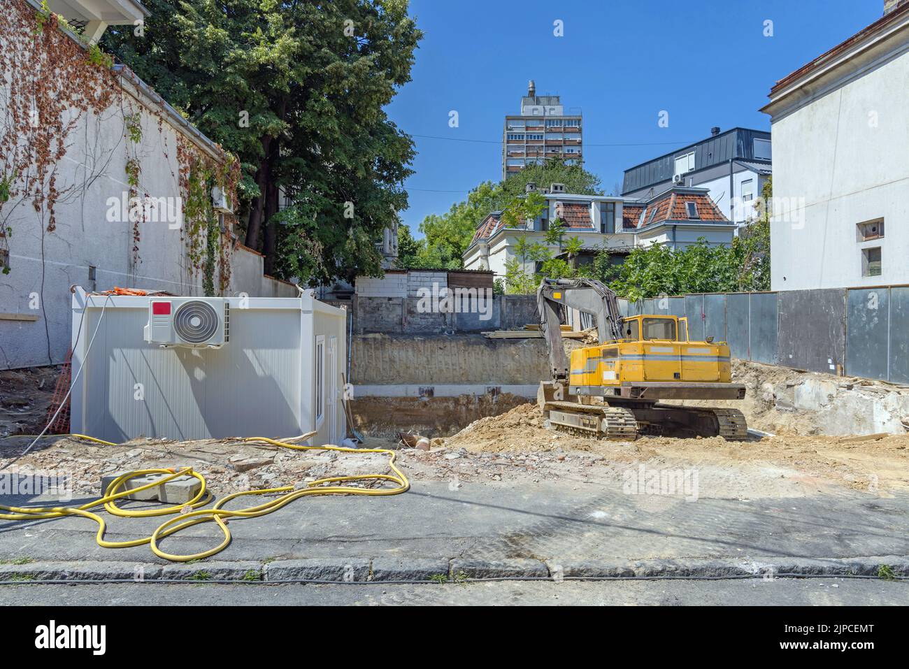 Container interrato ed escavatore cingolato in cantiere Foto Stock