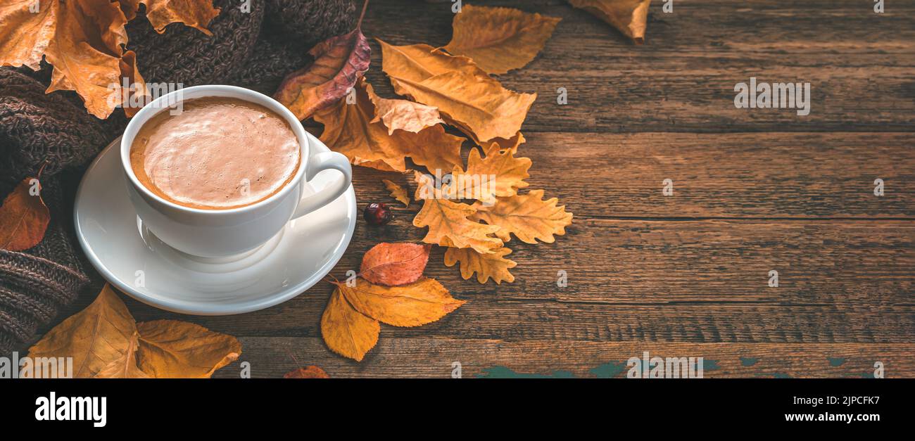 Cappuccino e fogliame autunnale su sfondo ligneo. Accogliente composizione autunnale. Foto Stock