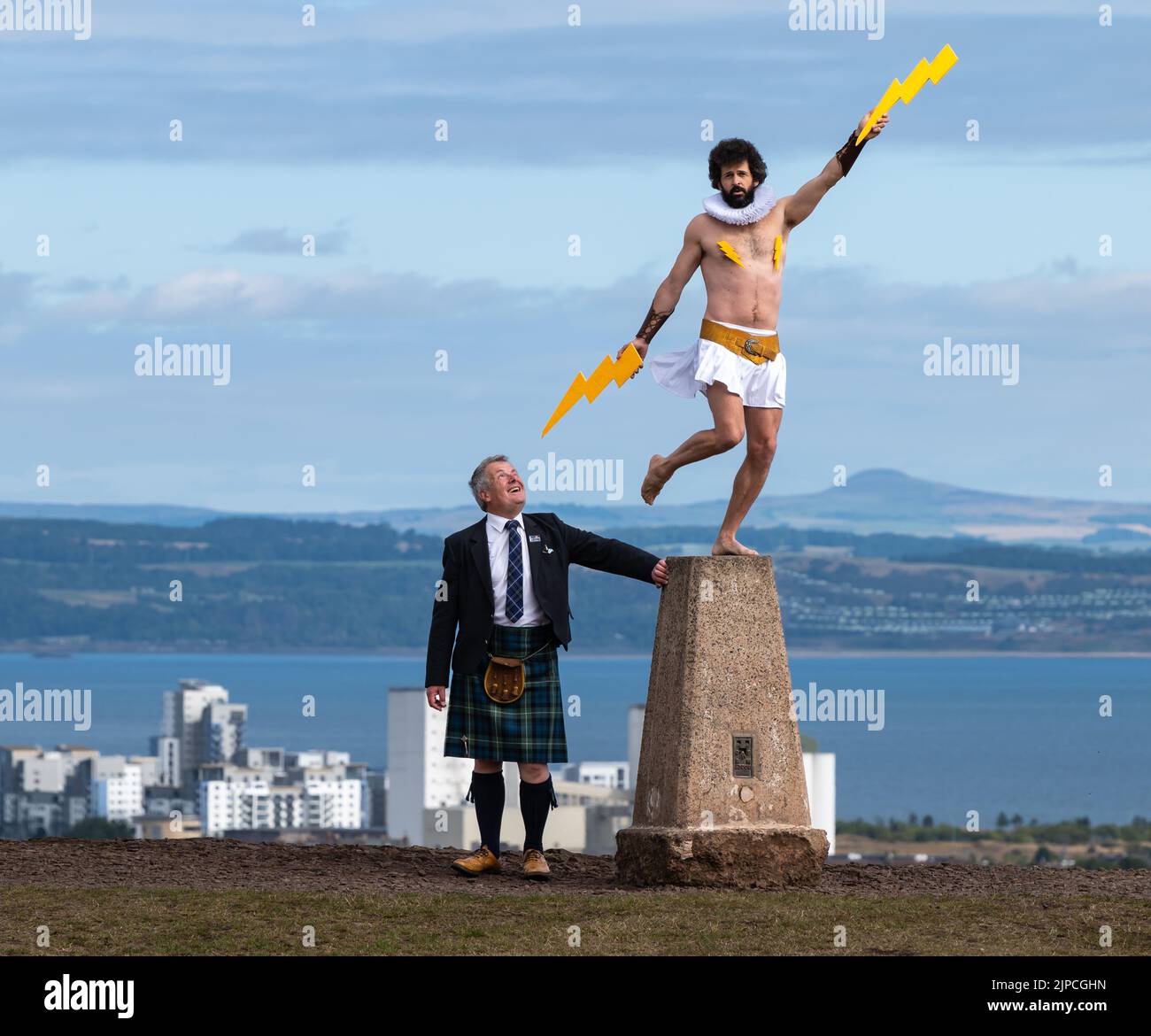 Edimburgo, Scozia, Regno Unito, 17th agosto 2022. Edinburgh Festival Fringe: Garry Starr, noto anche come Damien Warren-Smith, si esibisce a Calton Hill in piedi su un marcatore di triangolazione del sondaggio sugli ordigni. Nella foto: Dr Hugh Salveson, guida turistica di Edimburgo, ottiene un fulmine. Credit: Sally Anderson/Alamy Live News Foto Stock