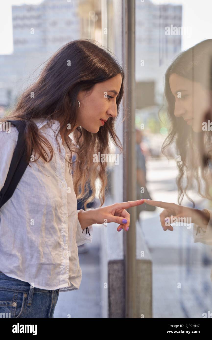 Primo piano ritratto di una giovane donna che guarda in una vetrina Foto Stock