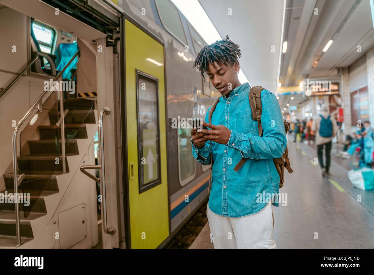 Ragazzo che guarda lo smartphone vicino all'ingresso del treno Foto Stock