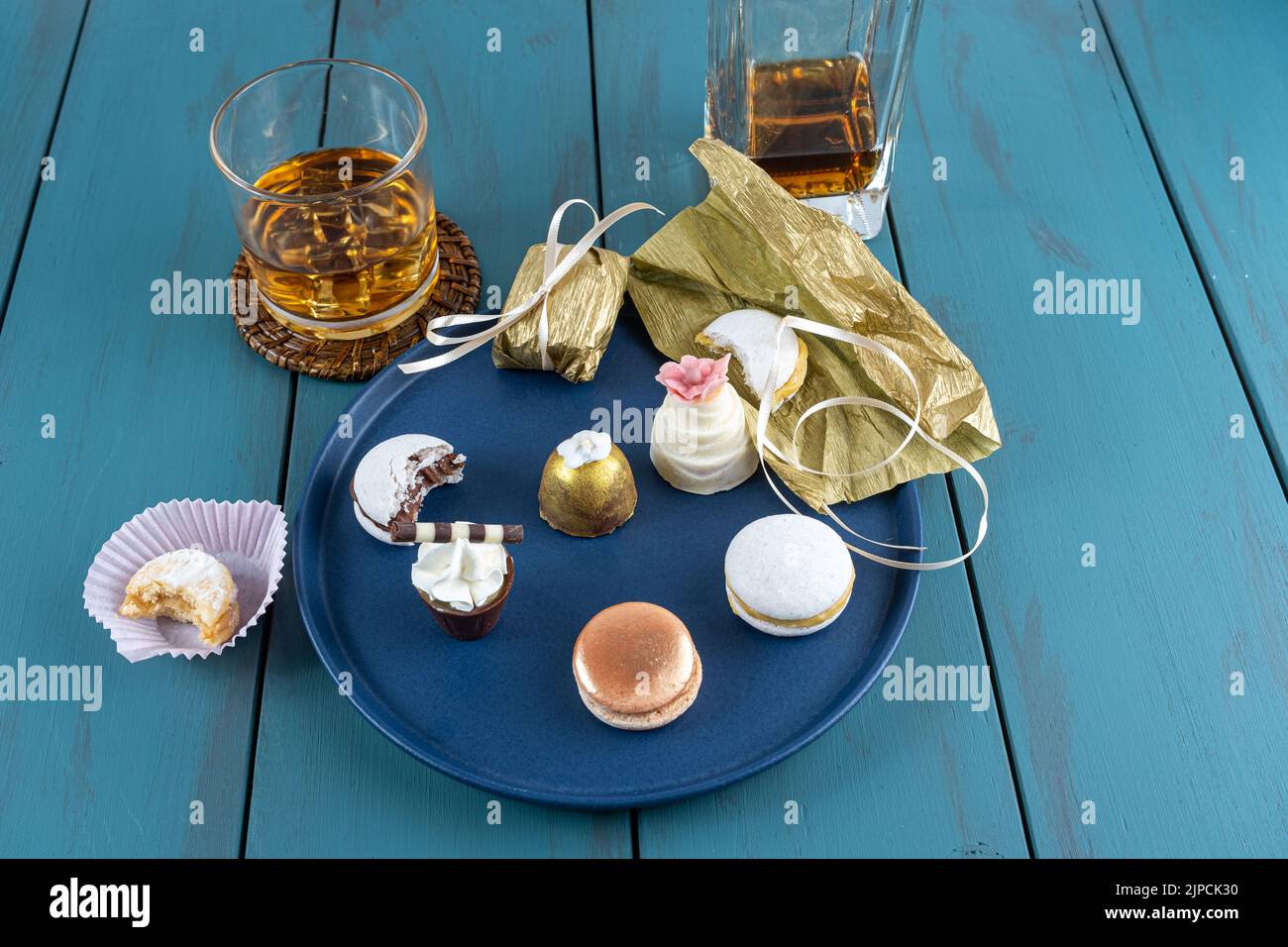 Macaron accanto al piccolo bicchiere di cioccolato con panna montata, cameo di noce, tartufo, bottiglia di whisky e bicchiere. Foto Stock