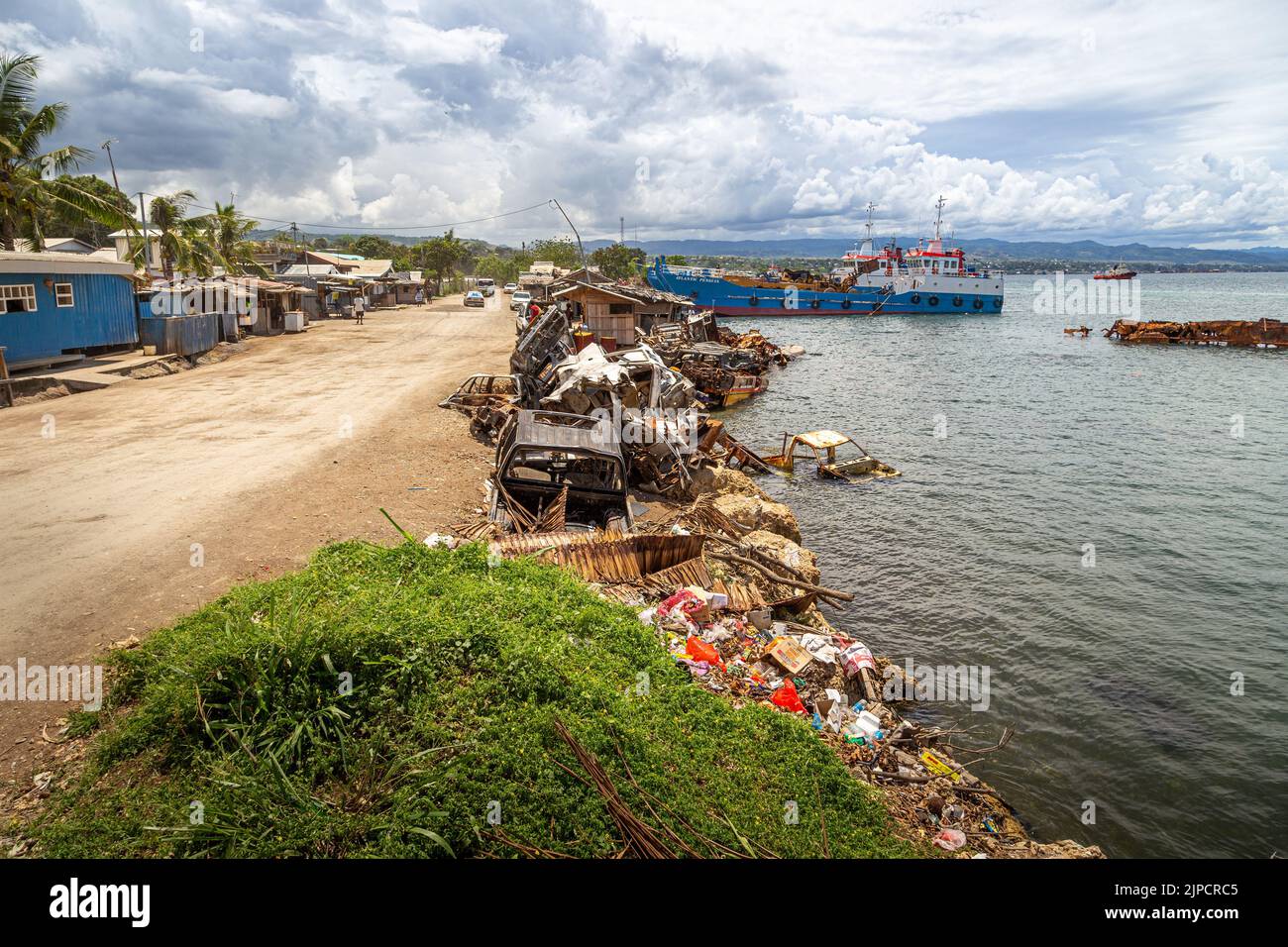 Rifiuti e relitti di automobili costeggiano la costa di un'area industriale di Honiara, capitale delle Isole Salomone. Foto Stock