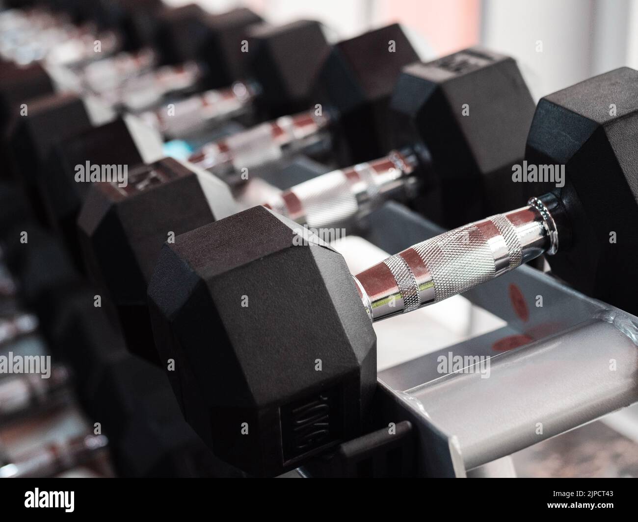 File di manubri pesanti in metallo su rack in palestra o club. Attrezzature per l'addestramento al peso. Concetto di sport e salute. Foto Stock