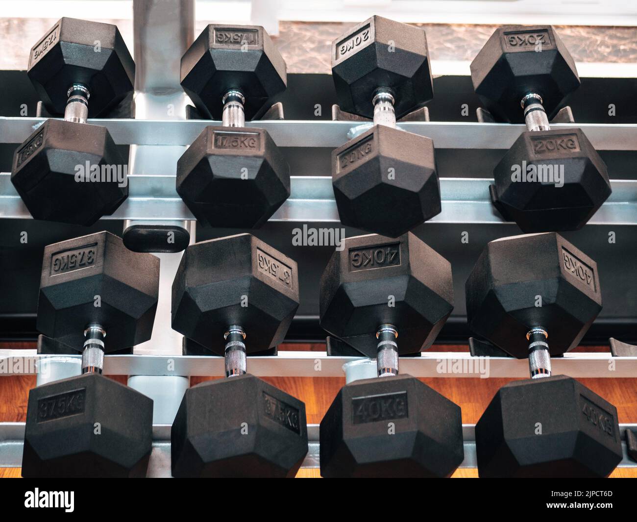 File di manubri pesanti in metallo su rack in palestra o club. Attrezzature per l'addestramento al peso. Concetto di sport e salute. Foto Stock