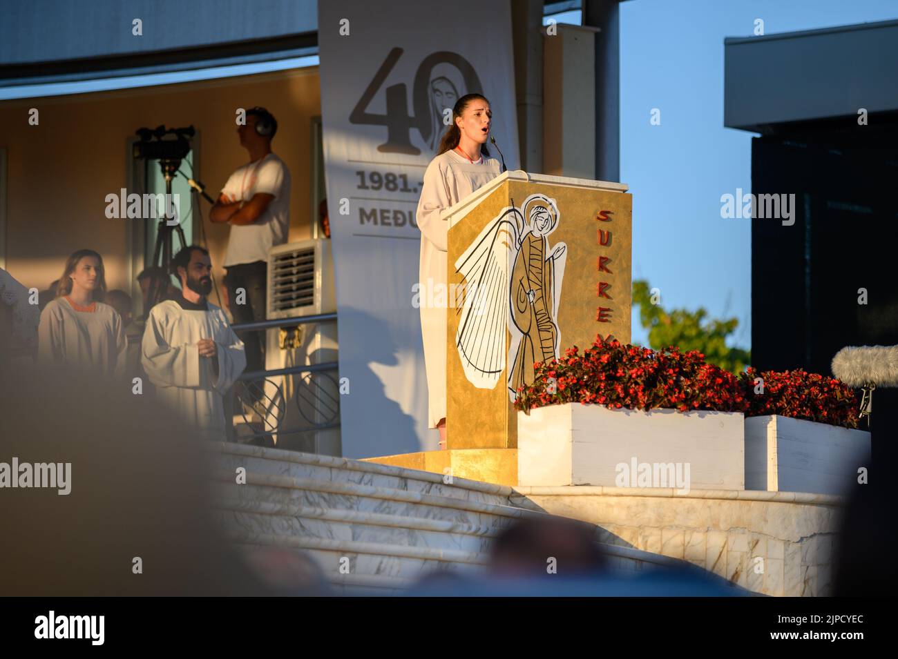 Una giovane donna che canta il salmo responsoriale durante la Santa Messa serale durante il Mladifest – la festa dei giovani – a Medjugorje. Foto Stock