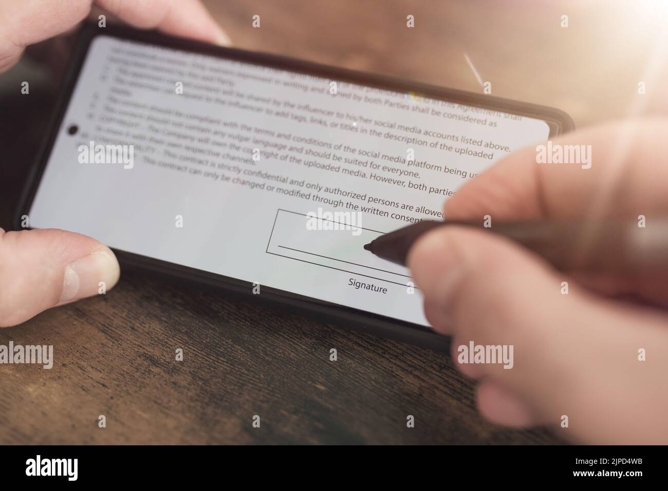vista ravvicinata della firma elettronica con stilo sullo schermo dello smartphone sullo sfondo di un tavolo in legno Foto Stock