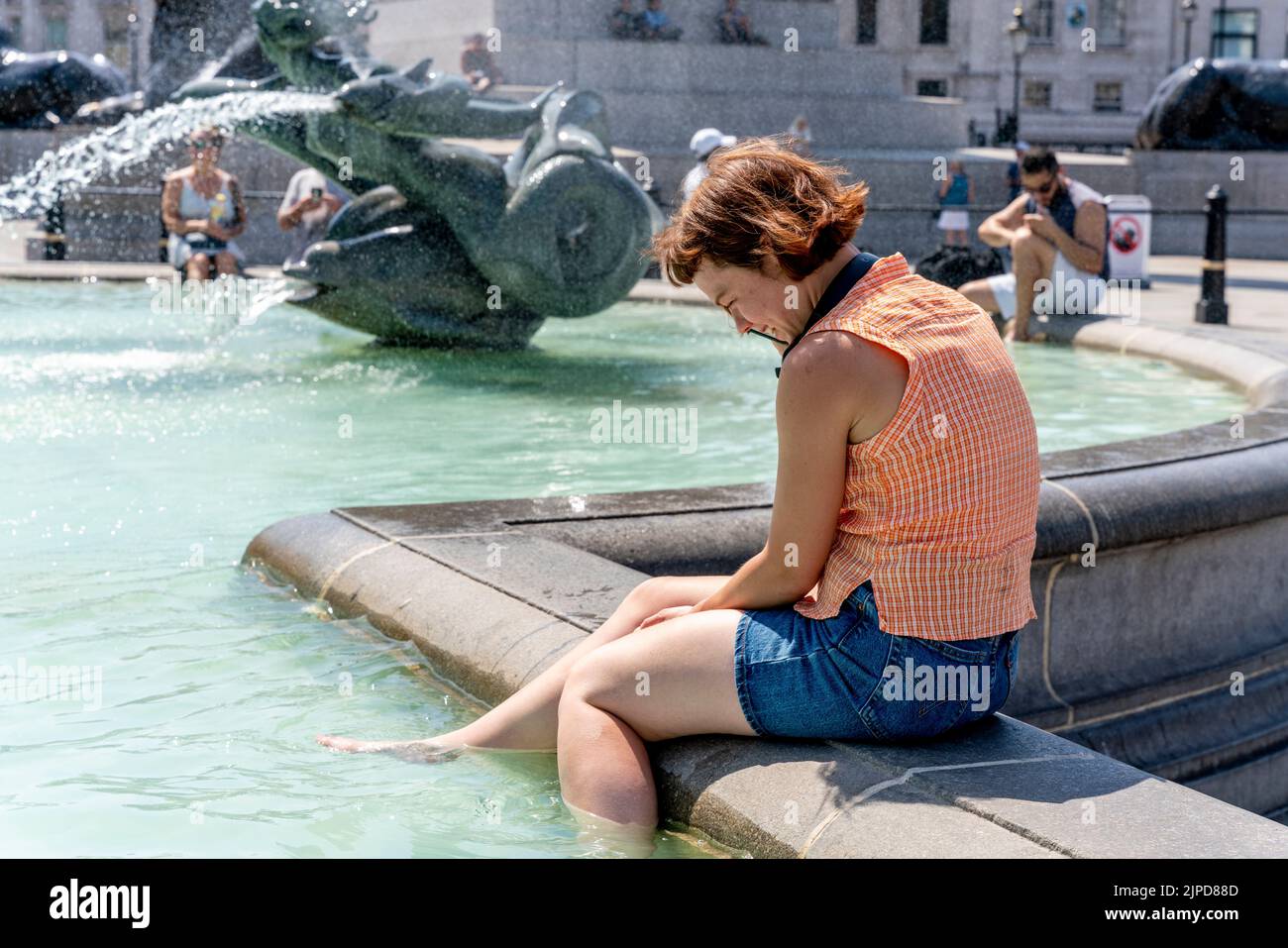 Una giovane donna si raffredda nelle fontane di Trafalgar Square il giorno più caldo mai registrato, Londra, Regno Unito Foto Stock