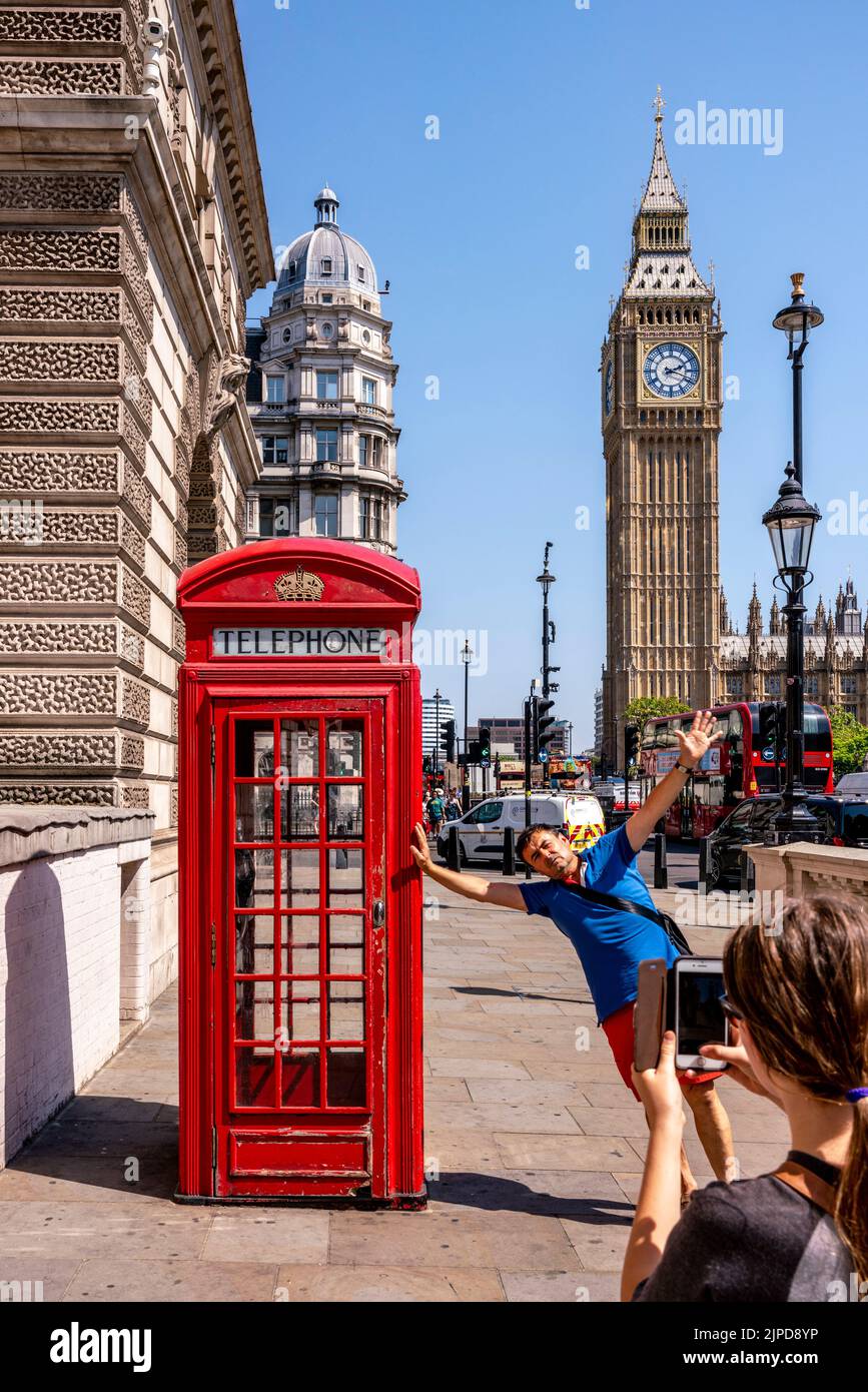 I turisti posano per le foto fuori Di Una tradizionale scatola telefonica rossa in Piazza del Parlamento durante Un Heatwave, Londra, Regno Unito. Foto Stock
