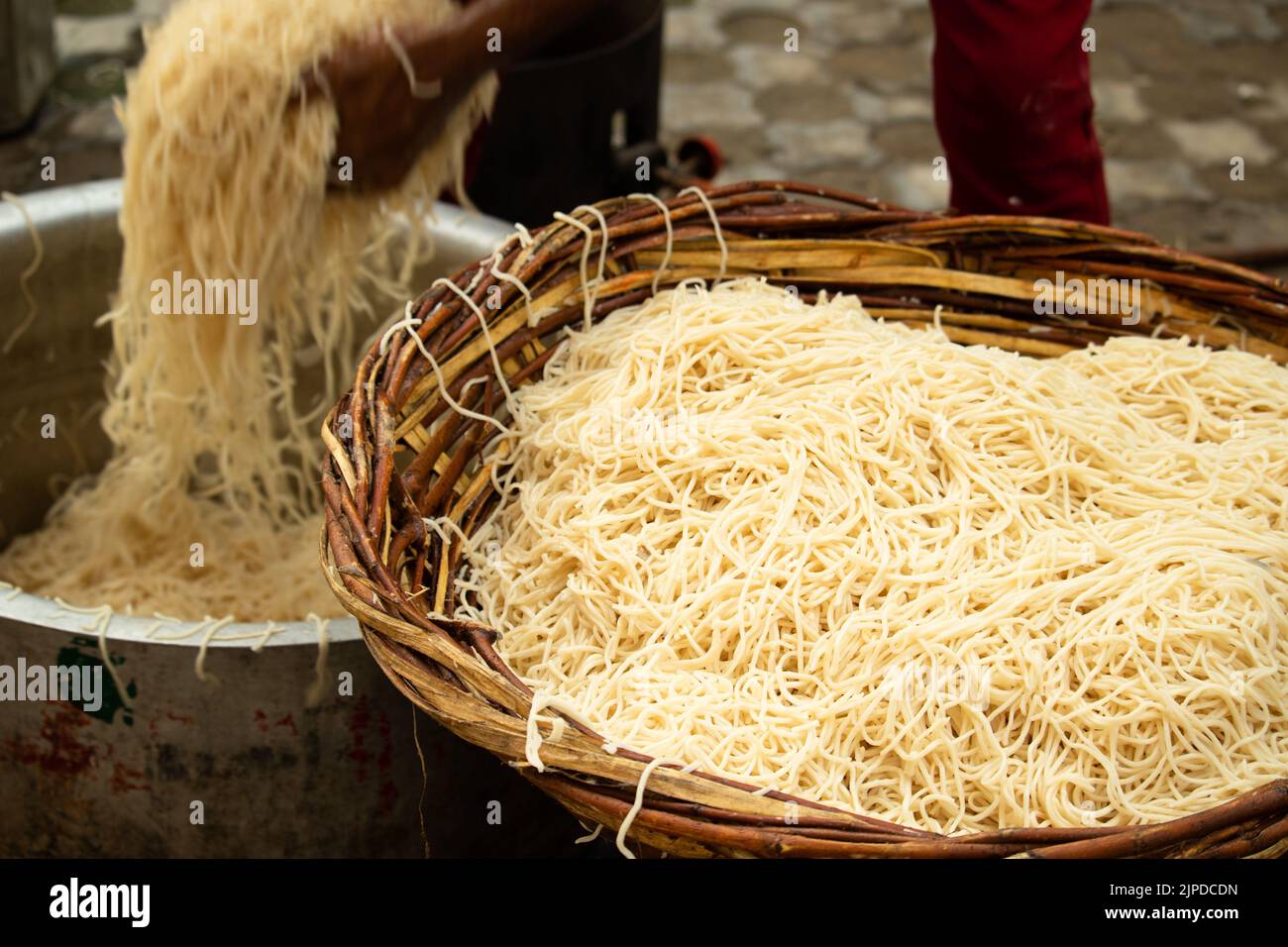 Cinese Schezwan anche chiamato Szechwan Veg Hakka Noodles Chowmin o Indian Veg Chow Mein essere lavato sciacquato in acqua in bambù Basket. Stile dhaba Bul Foto Stock
