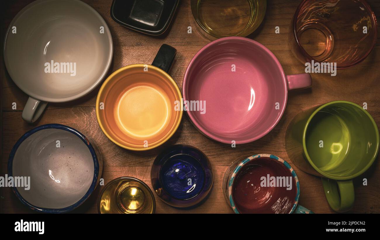 Home still life con tazze e bicchieri di diversi materiali e colori con luce a contrasto Foto Stock